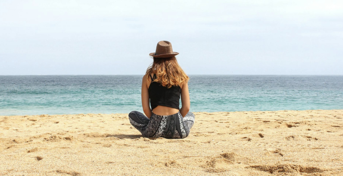 Persoon die langs de kustlijn wandelt, genietend van een rustige strandwandeling omringd door de zee en de horizon.