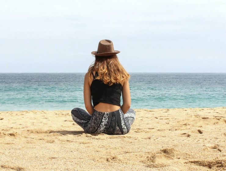 Persoon die langs de kustlijn wandelt, genietend van een rustige strandwandeling omringd door de zee en de horizon.