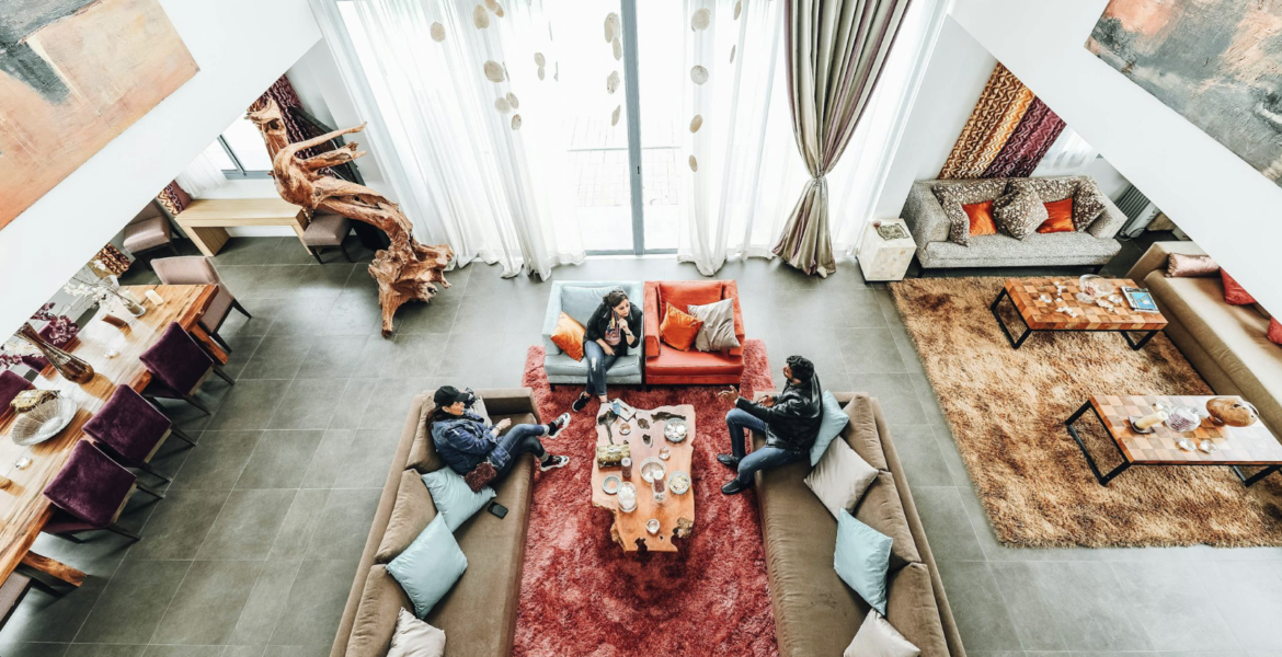 Persoon die ontspannen geniet van een comfortabele en gezellige hoek in huis, omgeven door zachte verlichting, planten en decoratieve accenten."