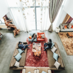 Persoon die ontspannen geniet van een comfortabele en gezellige hoek in huis, omgeven door zachte verlichting, planten en decoratieve accenten."