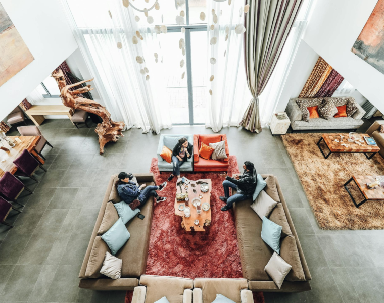 Persoon die ontspannen geniet van een comfortabele en gezellige hoek in huis, omgeven door zachte verlichting, planten en decoratieve accenten."